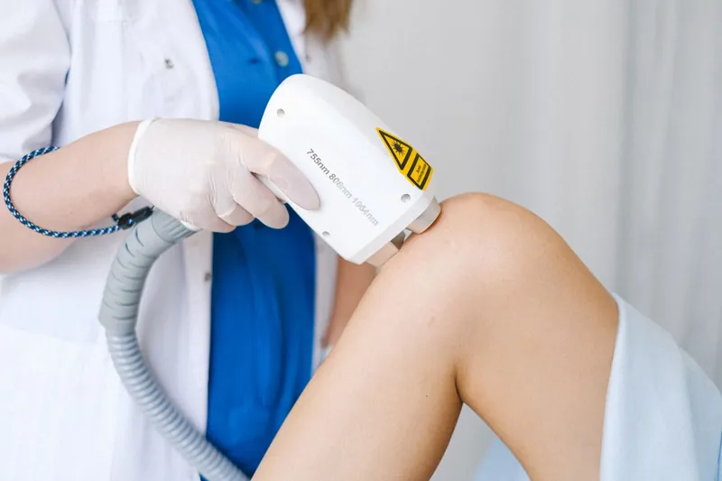 Fisioterapista che applica il manipolo del laser terapeutico sul ginocchio di una paziente